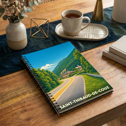 Carnet souvenir à spirales de la ville de Saint-Thibaud-de-Couz avec une illustration stylisée de sa route de montagne.
