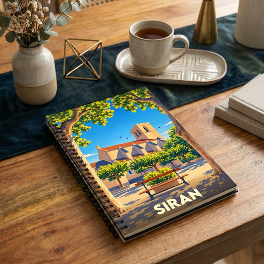 Carnet à spirales souvenir de la ville de Siran avec une illustration stylisée de son église et d'une place ensoleillée.