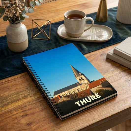 Carnet souvenir de la ville de Thuré avec une illustration stylisée de son église sous un ciel bleu.