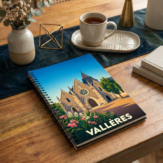 Carnet à spirales souvenir de la ville de Vallères avec une illustration stylisée de son église et de fleurs colorées.