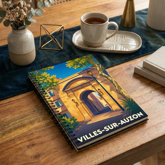 Carnet à spirales souvenir de Villes-sur-Auzon illustré par une vue stylisée d'une porte ancienne en pierre.
