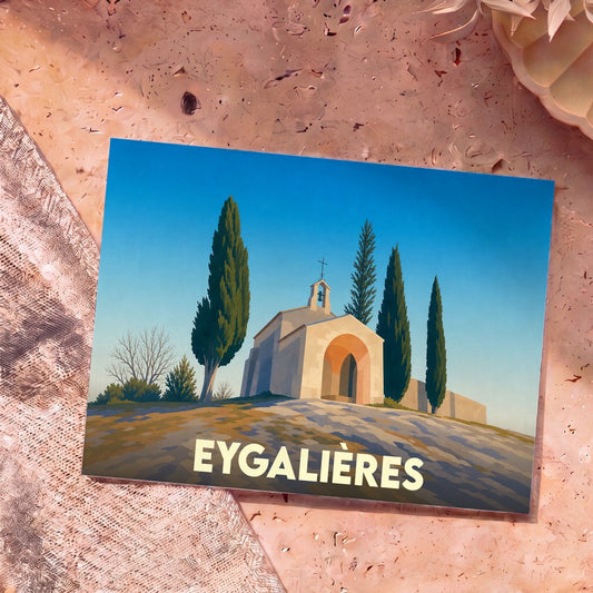 Carte postale souvenir de la ville d'Eygalières représentant une chapelle provençale entourée de cyprès dans un style graphique épuré.