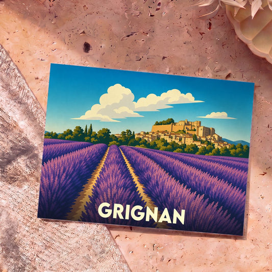 Carte postale souvenir de la ville de Grignan illustrant un champ de lavande au pied d'un village perché.