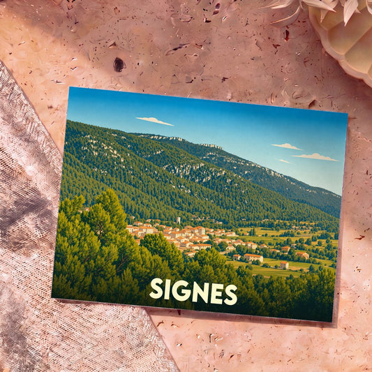 Carte postale souvenir de la ville de Signes illustrant le village niché au pied d'une montagne boisée.