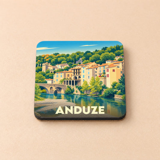 Dessous de verre souvenir de la ville d'Anduze avec une illustration stylisée d'un village provençal au bord de l'eau.