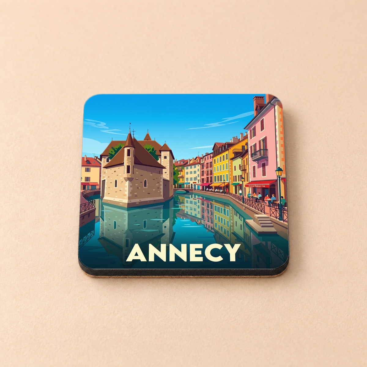 Dessous de verre souvenir de la ville d'Annecy avec une illustration stylisée de son célèbre monument historique au bord de l'eau.