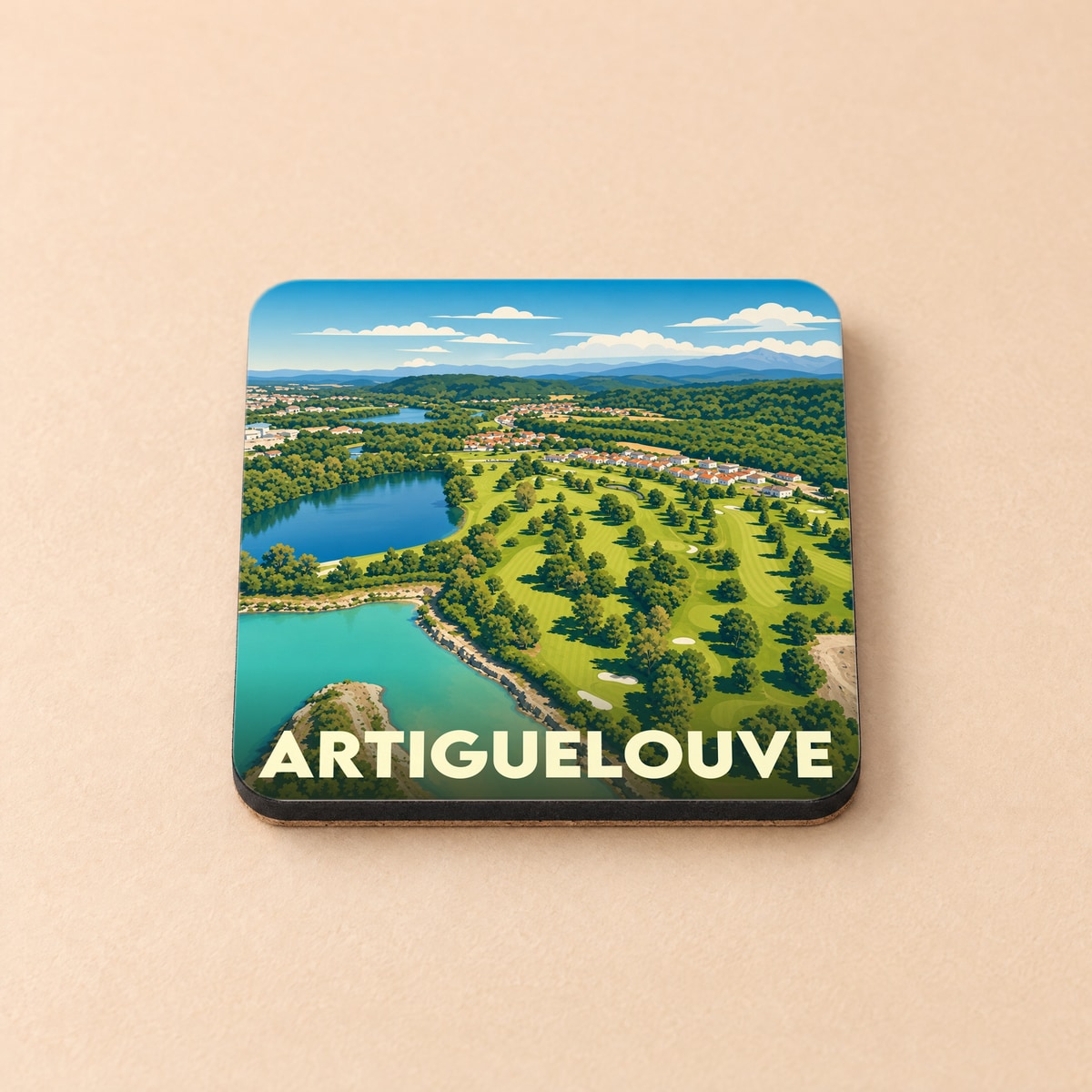Dessous de verre souvenir de la ville d'Artiguelouve illustré par une vue aérienne stylisée de son paysage vallonné et de ses plans d'eau.