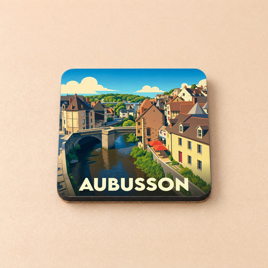 Dessous de verre souvenir de la ville d'Aubusson avec une illustration stylisée d'un pont et de maisons au bord de l'eau.