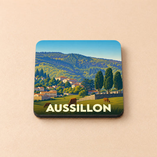 Dessous de verre souvenir de la ville d'Aussillon avec une illustration de paysages vallonnés et de maisons de village.