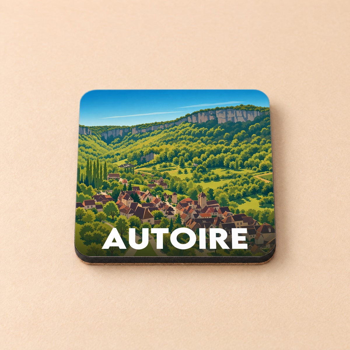 Dessous de verre souvenir de la ville d'Autoire avec une illustration stylisée d'un village niché dans une vallée verdoyante.