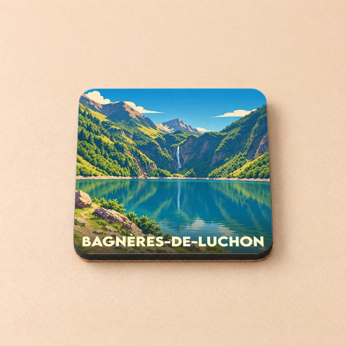 Dessous de verre souvenir de la ville de Bagnères-de-Luchon avec une illustration stylisée d'un lac de montagne et d'une cascade.