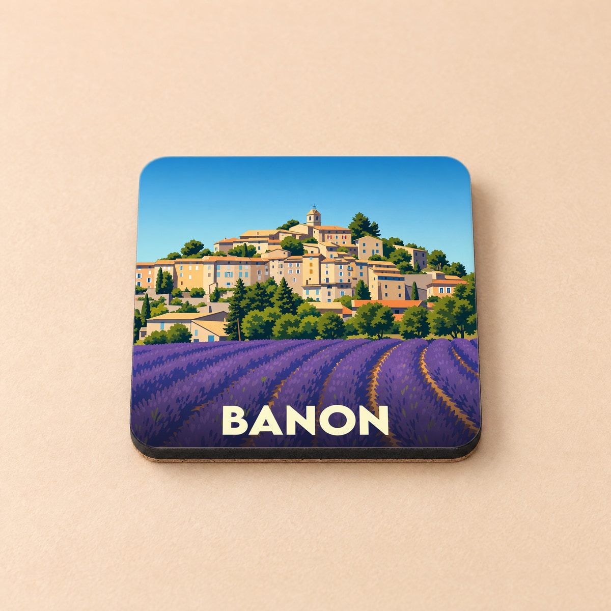 Dessous de verre souvenir de la ville de Banon illustré d'un village provençal surplombant des champs de lavande.