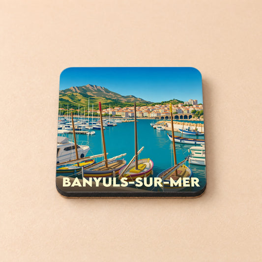 Dessous de verre souvenir de la ville de Banyuls-sur-Mer avec une illustration stylisée de son port et de ses montagnes.