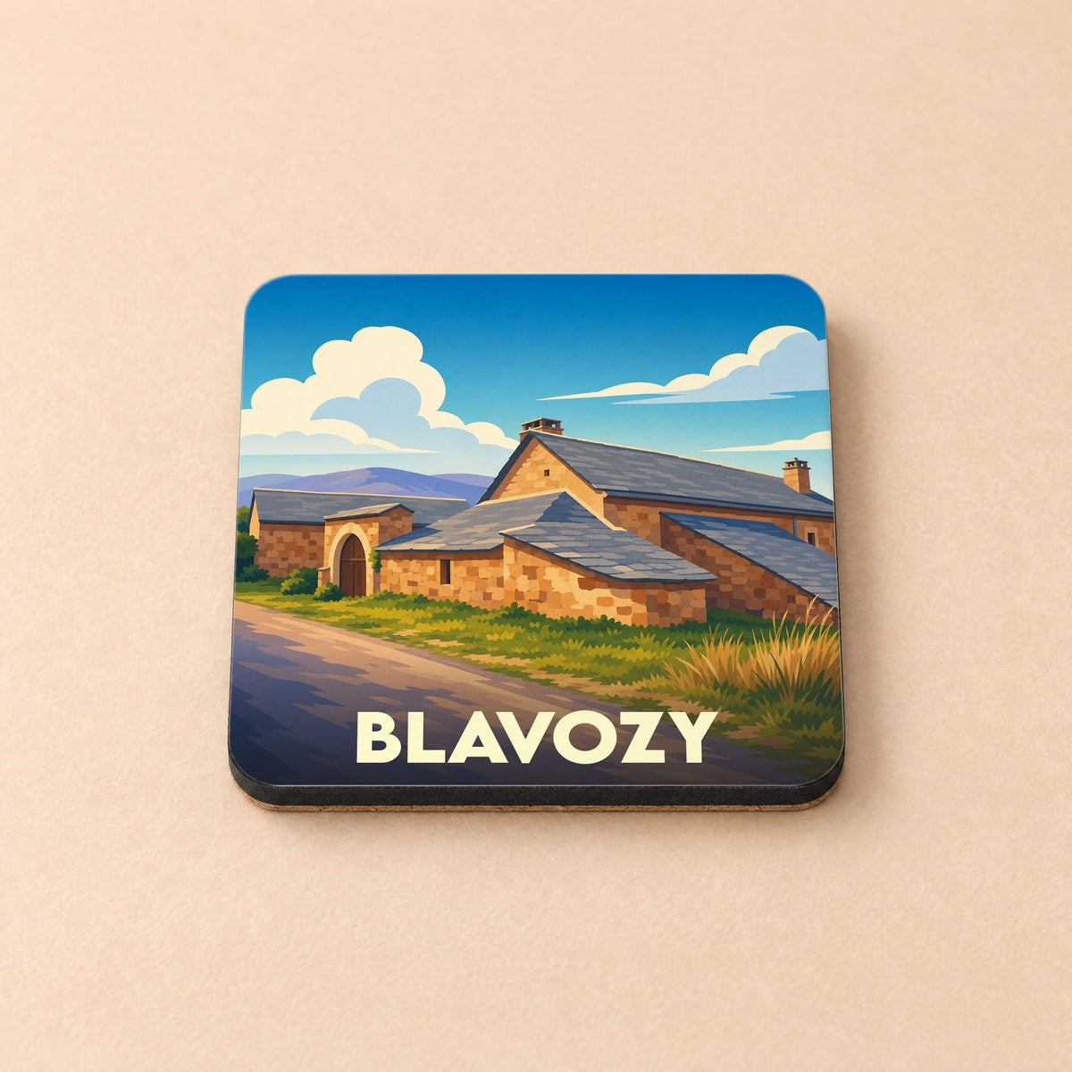 Dessous de verre souvenir de la ville de Blavozy illustré d'un paysage de bâtiments en pierre.