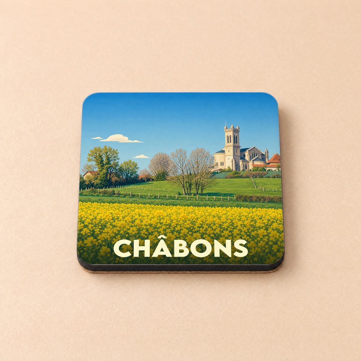 Dessous de verre souvenir de la ville de Châbons avec une illustration stylisée d'un paysage champêtre et de son église.