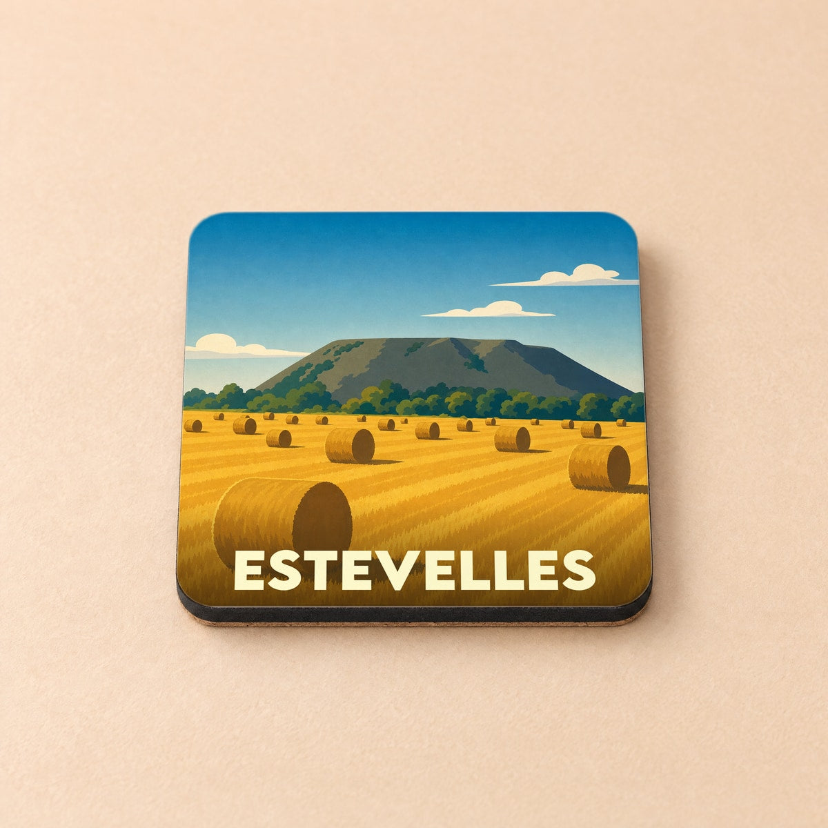 Dessous de verre souvenir de la ville d'Estevelles illustré d'un champ de meules de foin devant une colline.