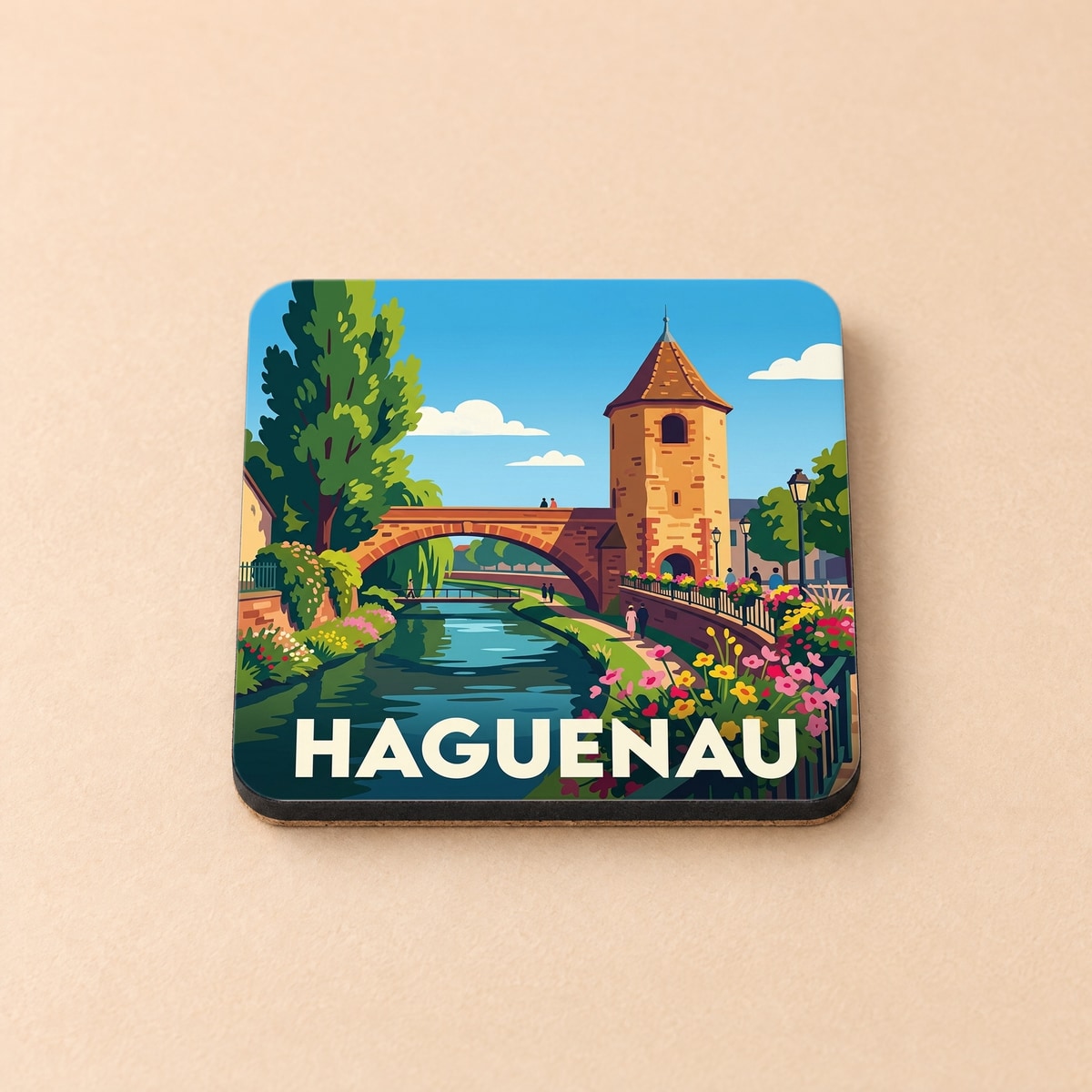 Dessous de verre souvenir de la ville de Haguenau avec une illustration stylisée montrant un pont et une tour médiévale.