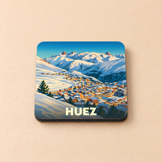 Dessous de verre souvenir de la ville de Huez avec une illustration stylisée d'un village de montagne enneigé.