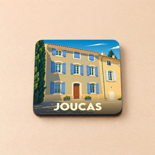 Dessous de verre souvenir de la ville de Joucas illustrant une maison provençale aux volets bleus.