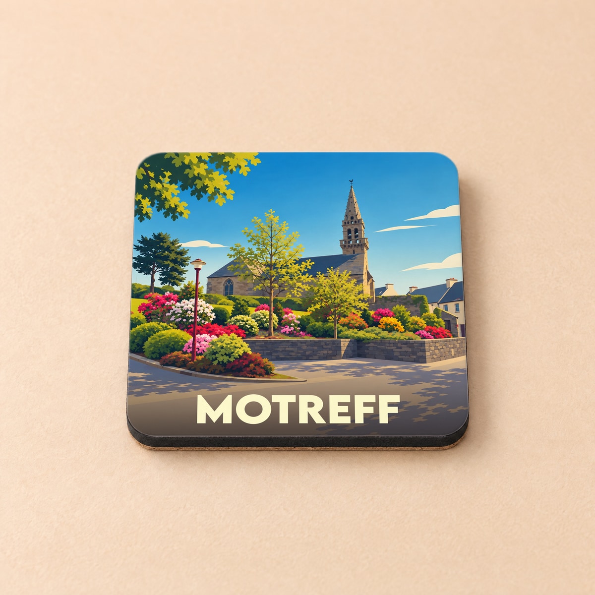 Dessous de verre souvenir de la ville de Motreff avec une illustration stylisée de son église et de jardins fleuris.