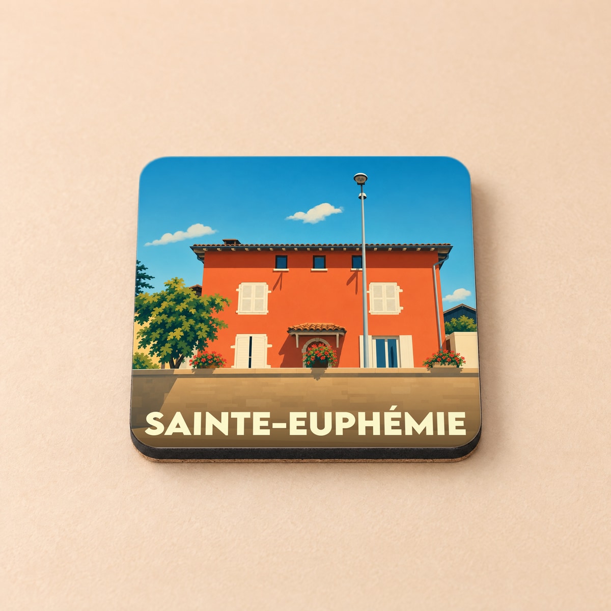 Dessous de verre souvenir de la ville de Sainte-Euphémie avec une illustration stylisée d'une maison colorée.