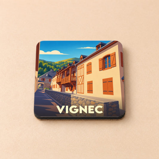 Dessous de verre souvenir de la ville de Vignec avec une illustration stylisée de maisons typiques pyrénéennes.