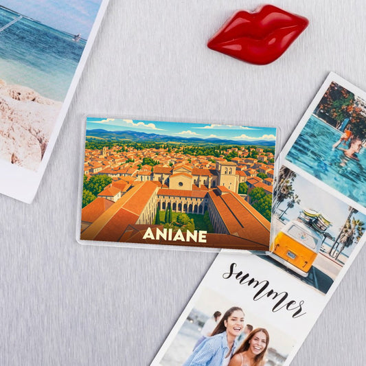 Magnet souvenir de la ville d'Aniane avec une illustration stylisée de ses toits orangés et de son abbaye.