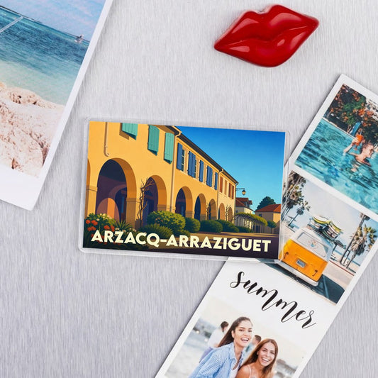Magnet souvenir de la ville d'Arzacq-Arraziguet illustré d'un bâtiment à arcades sous un ciel bleu.
