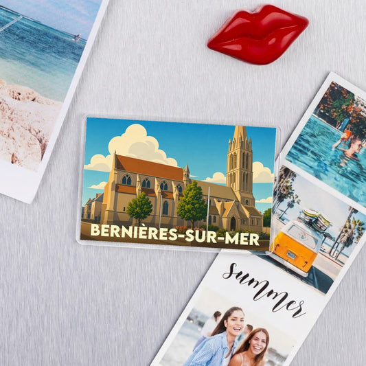 Magnet souvenir de la ville de Bernières-sur-Mer illustré par son église stylisée sous un ciel bleu.