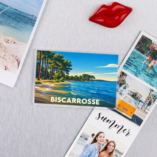 Magnet souvenir de la ville de Biscarrosse illustré d'un paysage côtier bordé de pins.