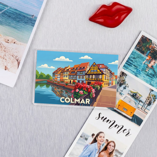 Magnet souvenir de la ville de Colmar avec une illustration stylisée de ses maisons à colombages au bord de l'eau.
