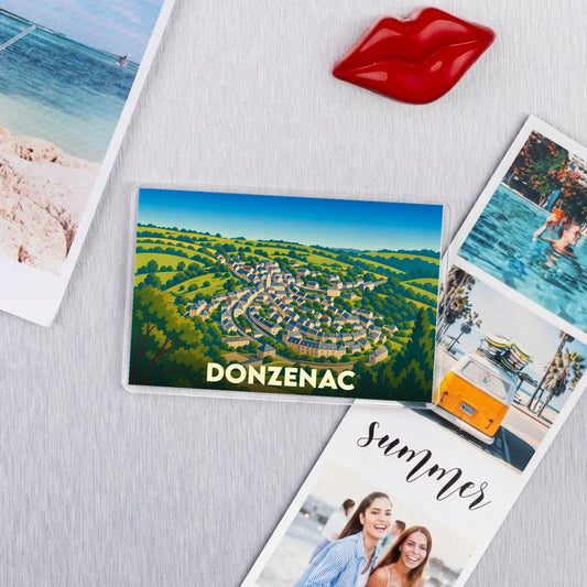Magnet souvenir de la ville de Donzenac avec une illustration stylisée d'un village niché dans des collines verdoyantes.
