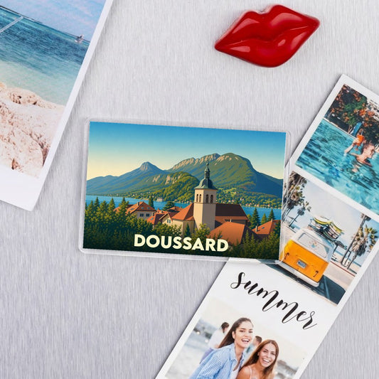 Magnet souvenir de la ville de Doussard avec une illustration stylisée d'un paysage montagneux.