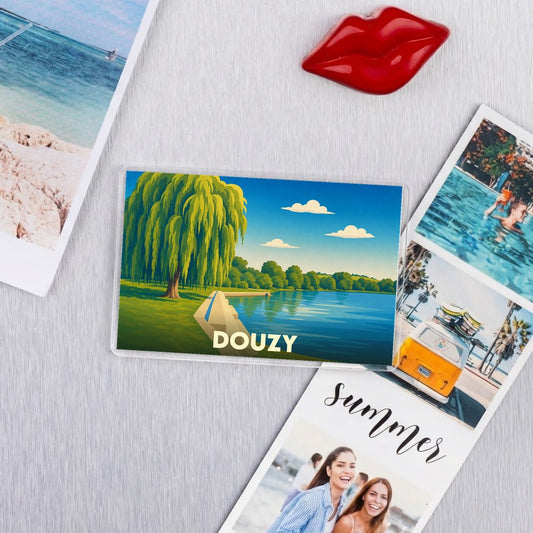 Magnet souvenir de la ville de Douzy avec une illustration stylisée d'un lac bordé d'un saule pleureur.