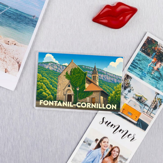 Magnet souvenir de la ville de Fontanil-Cornillon avec une illustration stylisée de son église sur fond de montagnes.