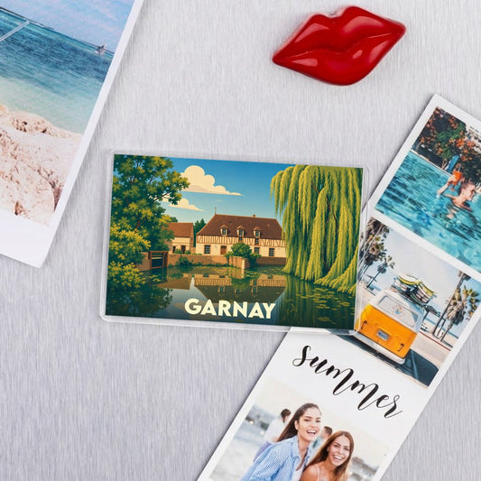 Magnet souvenir de la ville de Garnay avec une illustration colorée d'une bâtisse au bord de l'eau.