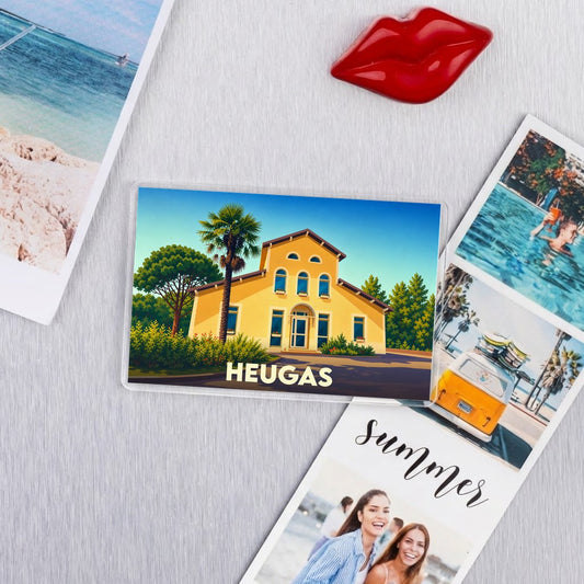 Magnet souvenir de la ville de Heugas avec une illustration stylisée d'une maison landaise sous le soleil.