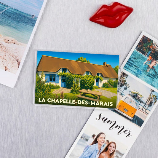Magnet souvenir de La Chapelle-des-Marais illustrant une chaumière traditionnelle aux volets bleus.