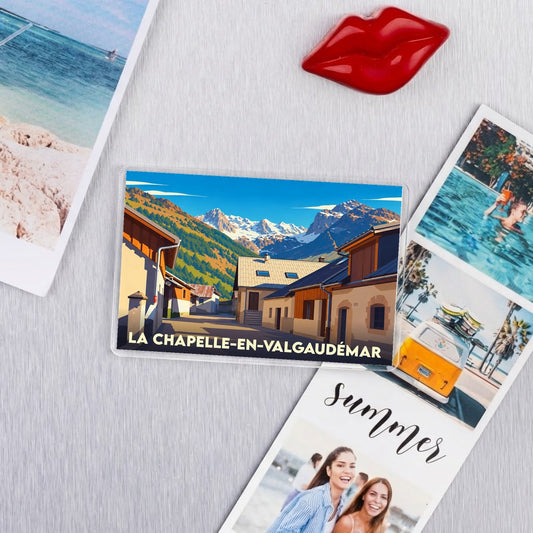Magnet souvenir de La Chapelle-en-Valgaudémar avec une illustration stylisée du village et des montagnes enneigées.