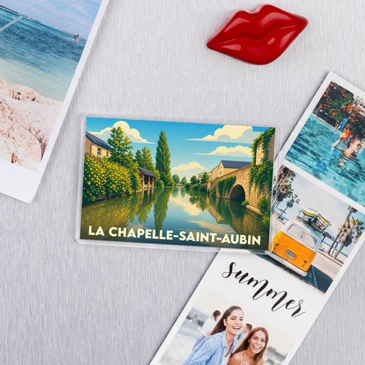 Magnet souvenir de la ville de La Chapelle-Saint-Aubin avec une illustration stylisée d'un cours d'eau bordé de verdure.