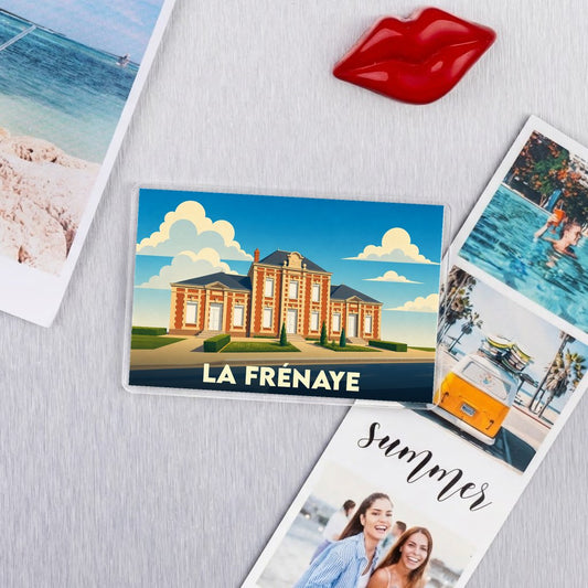Magnet souvenir de la ville de La Frénaye avec une illustration stylisée d'un bâtiment remarquable.