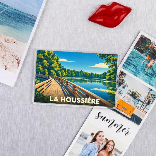 Magnet souvenir de la ville de La Houssière avec une illustration stylisée d'un ponton sur un lac.