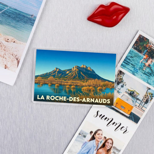 Magnet souvenir de la ville de La Roche-des-Arnauds avec une illustration de montagne surplombant un lac.