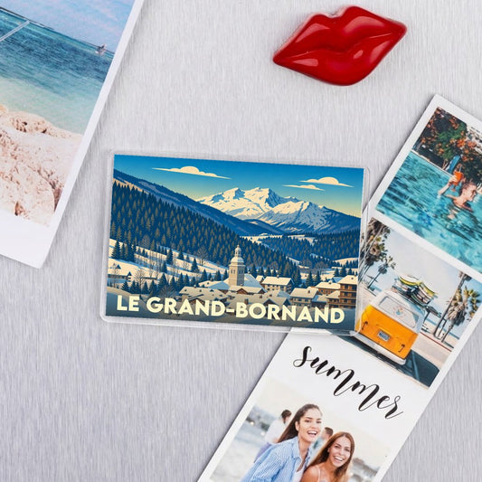 Magnet souvenir de la ville de Le Grand-Bornand avec une illustration stylisée d'un paysage de montagne enneigé.