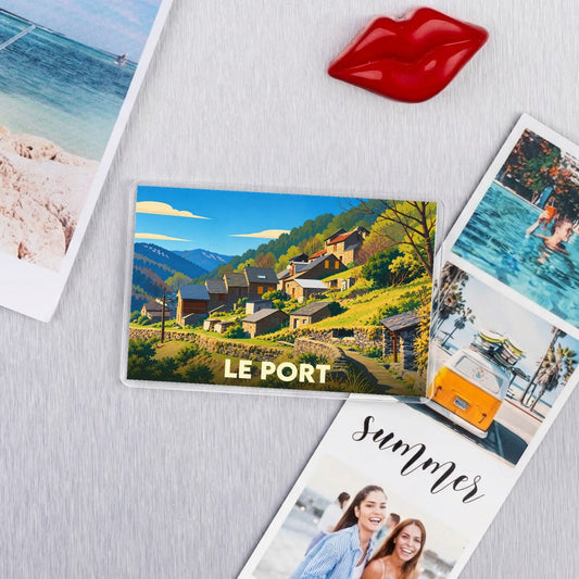 Magnet souvenir de la ville de Le Port avec une illustration stylisée d'un village de montagne.