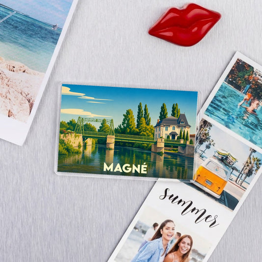 Magnet souvenir de la ville de Magné avec une illustration stylisée d'un pont et d'une maison au bord de l'eau.