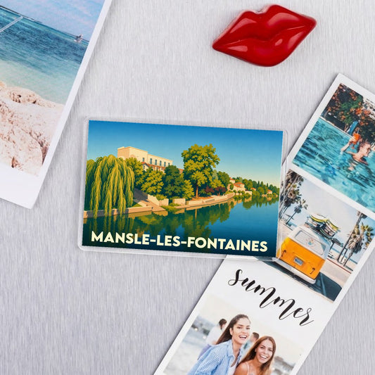 Magnet souvenir de la ville de Mansle-les-Fontaines avec une illustration stylisée d'un bord de rivière.