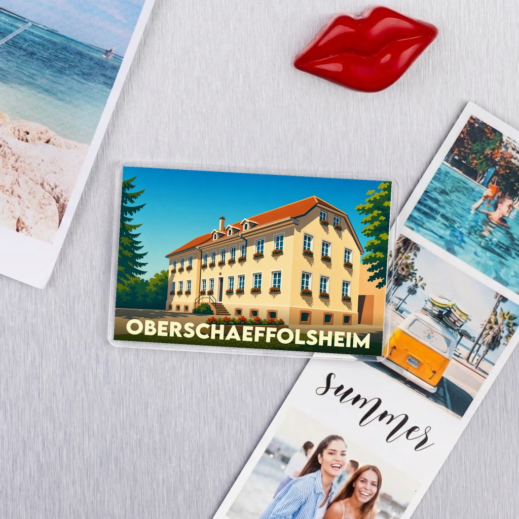 Magnet souvenir de la ville d'Oberschaeffolsheim arborant une illustration colorée et stylisée d'un bâtiment traditionnel alsacien.