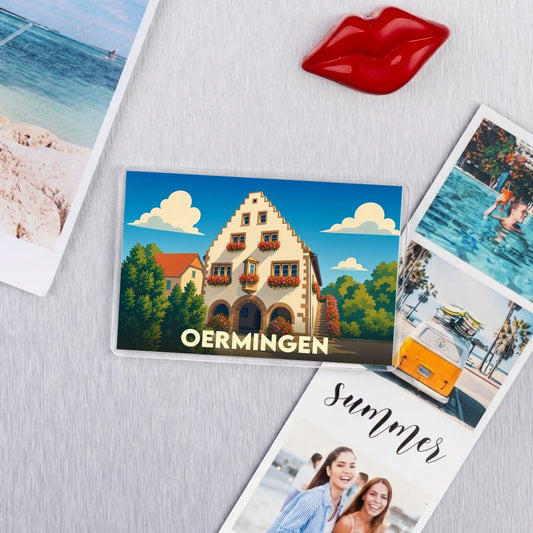 Magnet souvenir de la ville d'Oermingen avec une illustration stylisée d'un bâtiment traditionnel alsacien.