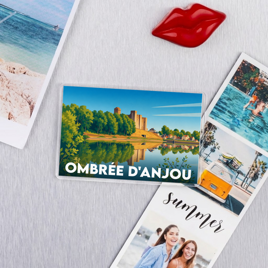 Magnet souvenir de la ville d'Ombrée d'Anjou avec une illustration stylisée d'un château au bord de l'eau.